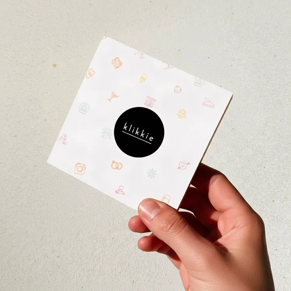 A hand holding a klikkie gift card, ready to give as a personal photo book present